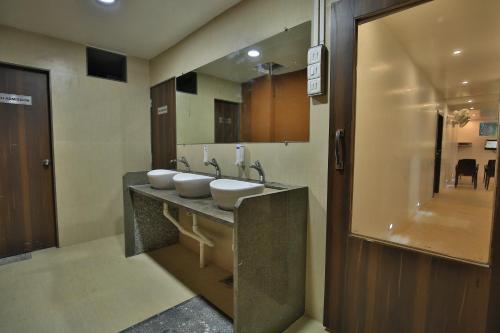 a bathroom with three sinks and a large mirror at Suvidha Ghar AC DORMITORY in Surat