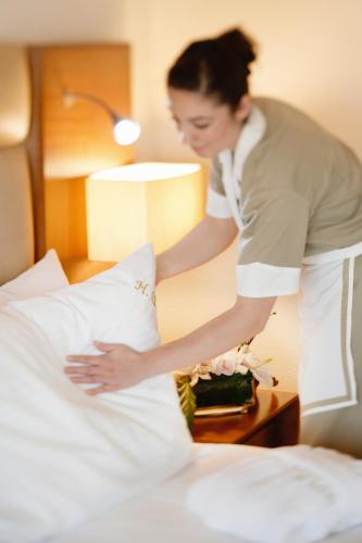 a woman putting a pillow on top of a bed at Mövenpick Hotel Izmir in Izmir