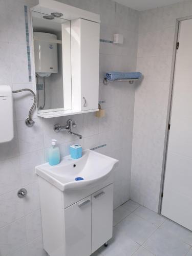 une salle de bains blanche avec un lavabo et un miroir dans l'établissement Paradise, à Vrnjačka Banja