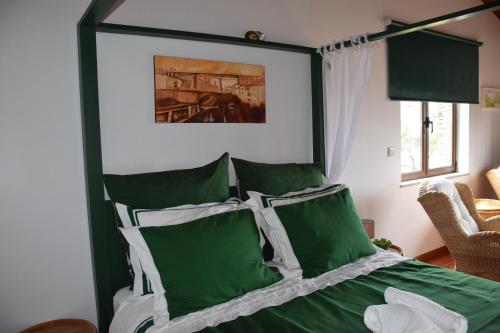 A Casa da Sofia في فيلا ريال: غرفة نوم بسرير ومخدات خضراء وبيضاء