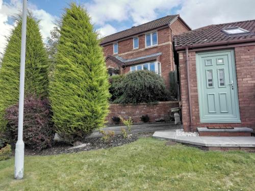 a brick house with a blue door and trees at Executive Annex - Dunfermline in Dunfermline