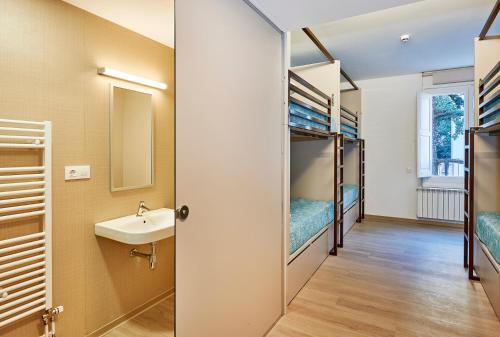Pokój z łóżkami piętrowymi, umywalką i lustrem w obiekcie Alberg Abat Oliba w mieście Montserrat