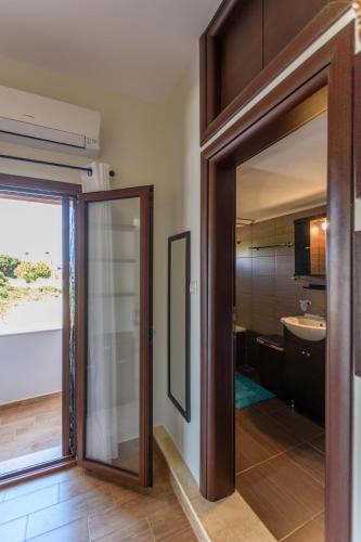 a glass door leading to a bathroom with a sink at Poppy flower in Stalís