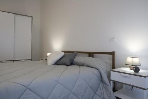 a white bedroom with a bed and a nightstand with a lamp at TalialETNA Apartments in Nicolosi