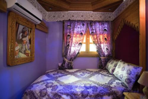 a purple bedroom with a bed with a window at Riad Mehdi Meknès in Meknès