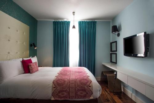 una camera con letto e TV a schermo piatto di City Suites a Londra
