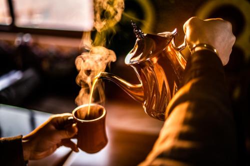 a person holding a cup of coffee with a tea pot at Moroccan House in Marrakech