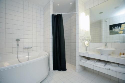 a white bathroom with a tub and a sink at OnlySleep Oksebrovej in Slagelse