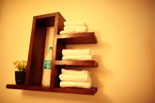 a wooden towel shelf with towels on a wall at Hotel Highnest in Singapperumālkovil