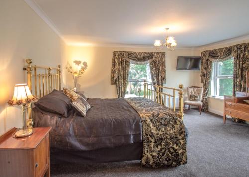 a bedroom with a bed and a desk and windows at Altahammond House in Carrickfergus