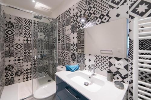 uma casa de banho com paredes em azulejo preto e branco e um lavatório. em L'ALCÔVE Saint GEORGES ★ Au cœur de TOULOUSE em Toulouse