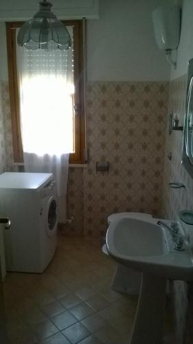 a bathroom with a toilet and a sink and a window at Appartamento grazioso e confortevole a Orbetello (GR) in Orbetello