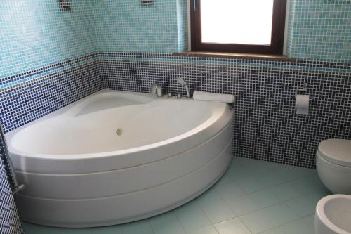 a white tub in a bathroom with a toilet at Villa i Minnulareddi in Giardini Naxos