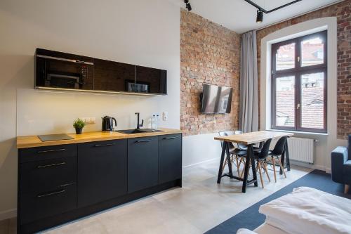 kuchnia z czarnymi szafkami i stołem w pokoju w obiekcie Loft Apartments Poznań w Poznaniu