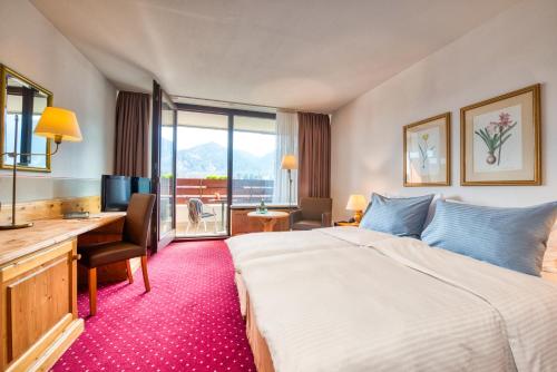 a hotel room with a bed and a desk and a computer at Arabella Brauneck Hotel in Lenggries