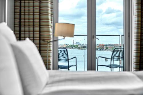 Schlafzimmer mit Blick auf das Wasser durch die Fenster in der Unterkunft Copenhagen Island Hotel in Kopenhagen