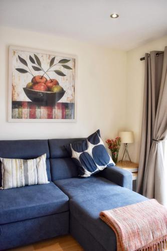 a living room with a blue couch and a bowl of fruit at Ramblers Rest Modern Cottage-Perfect Views of Ben Nevis in Fort William