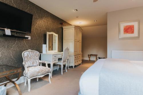 a bedroom with a bed and a desk and a tv at Hall Farm Hotel And Restaurant in Ashby cum Fenby