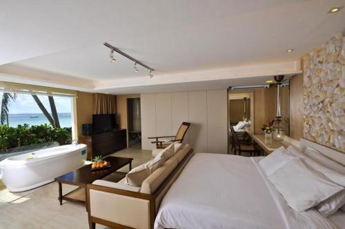 a bedroom with a large bed and a bathtub and a living room at Estacio Uno in Boracay