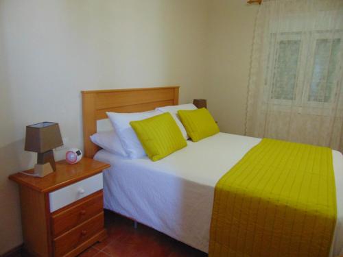 a bedroom with a bed with yellow pillows and a night stand at Aeropuerto in Carrizal
