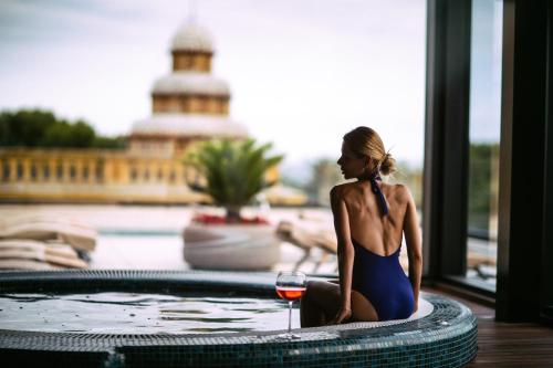 a woman sitting in a swimming pool with a glass of wine at Boutique Hotel Élke Spa Superior in Sant Feliu de Guixols