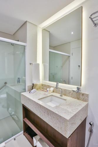 a bathroom with a sink and a large mirror at Transamerica Collection Goiania in Goiânia