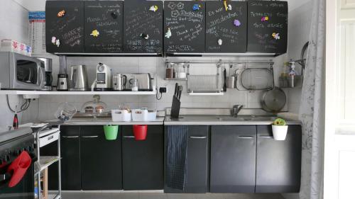 a kitchen with black cabinets and a sink at Three Rooms in Messina