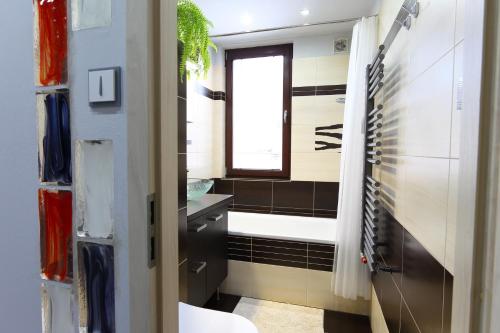 ein Bad mit einer Badewanne, einem Waschbecken und einem Fenster in der Unterkunft Apartmán 77 in Loučná nad Desnou