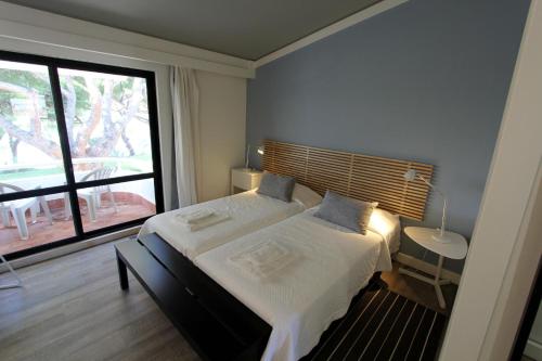 1 dormitorio con cama grande y ventana grande en Victory Village Club, Quinta do Lago en Quinta do Lago