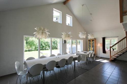 a dining room with white tables and chairs and windows at Villa M in Simrishamn