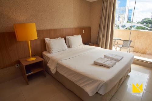 a bedroom with a bed with a lamp and a window at Brasília Imperial Hotel e Eventos in Brasilia