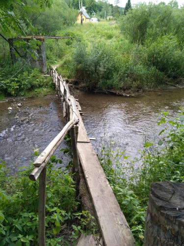 a wooden bridge over a river in a field at Dolina Rosy in Ustrzyki Dolne