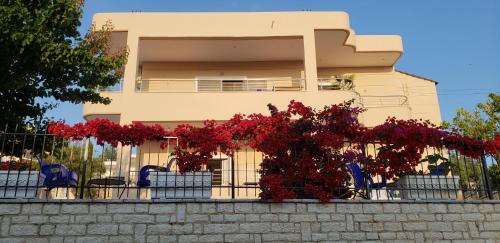 ein Gebäude mit roten Blumen vor einem Zaun in der Unterkunft Villa Kela in Ksamil