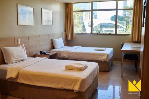 a hotel room with two beds and a window at Brasília Imperial Hotel e Eventos in Brasilia