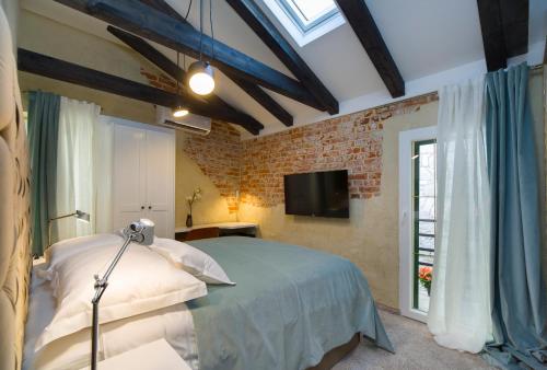 a bedroom with a bed and a tv and a brick wall at LAmenta in Split