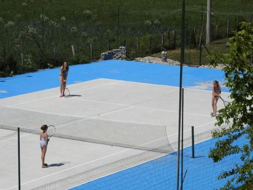 three women playing tennis on a tennis court at Exo Log Cottage in Jezero