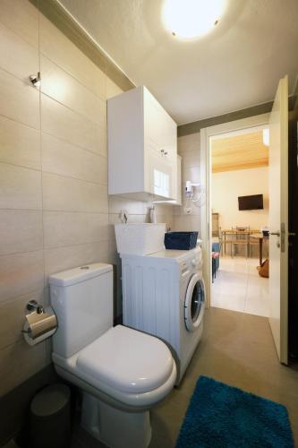 a bathroom with a toilet and a washing machine at Under the Windmills in Kondiás