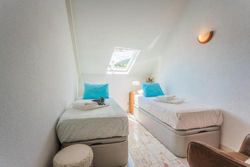 two beds in a small room with blue pillows at Estrela de Sesimbra in Sesimbra