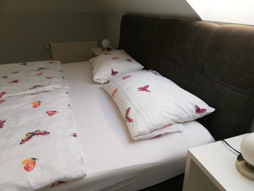 a bed with white pillows with butterflies on it at Ferienwohnung Panoramablick in Lieser