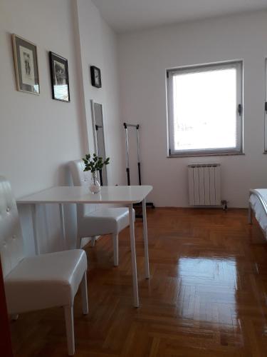 a white room with a table and chairs and a window at Apartman Dunja NS 2 in Novi Sad