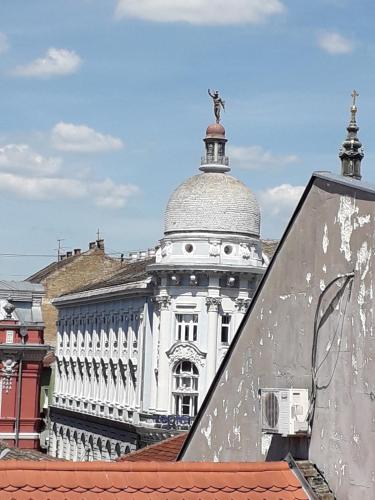 a large white building with a statue on top of it at Apartman Dunja NS 2 in Novi Sad