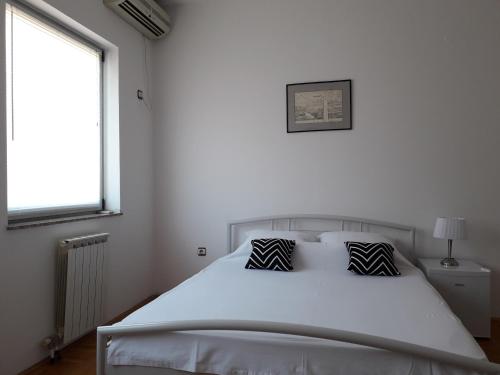 a bedroom with a white bed with two pillows on it at Apartman Dunja NS 2 in Novi Sad