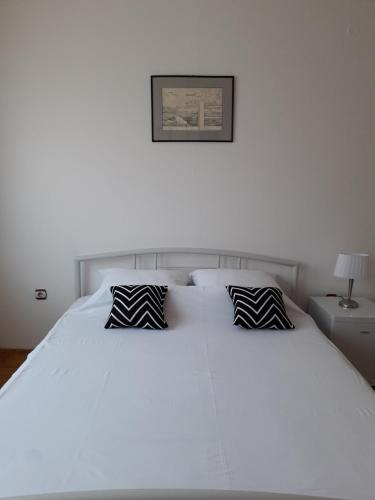 a white bed with black and white pillows on it at Apartman Dunja NS 2 in Novi Sad