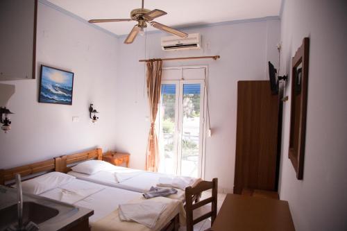 1 dormitorio con 1 cama, ventilador de techo y ventana en Hotel Asteria, en Agios Kirykos