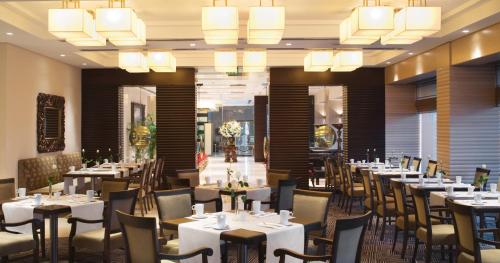 a dining room with tables and chairs and chandeliers at Mövenpick Hotel Izmir in Izmir