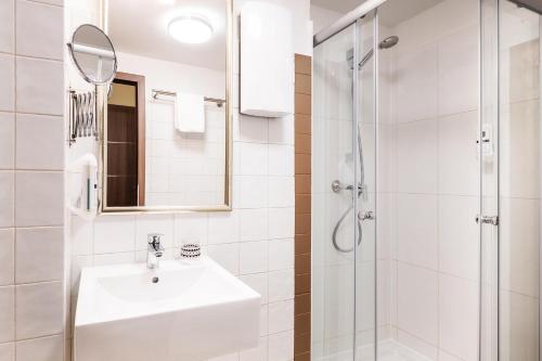 a white bathroom with a sink and a shower at Schroeders City-Style-Hotel in Trier