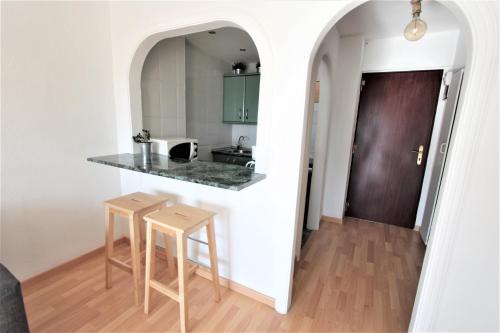 cocina con encimera y 2 taburetes en 325 Agata Apartamentos - Piscina y Playa -CANALES DE TV INTERNACIONALES, en Benalmádena