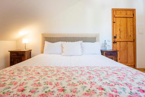 a bedroom with a large bed with a floral bedspread at Lagar do Sapateiro in Fontes