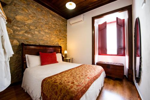 a bedroom with a bed and a stone wall at Lagar do Sapateiro in Fontes