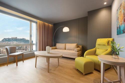 a living room with a couch and a table and chairs at Wyndham Grand Athens in Athens